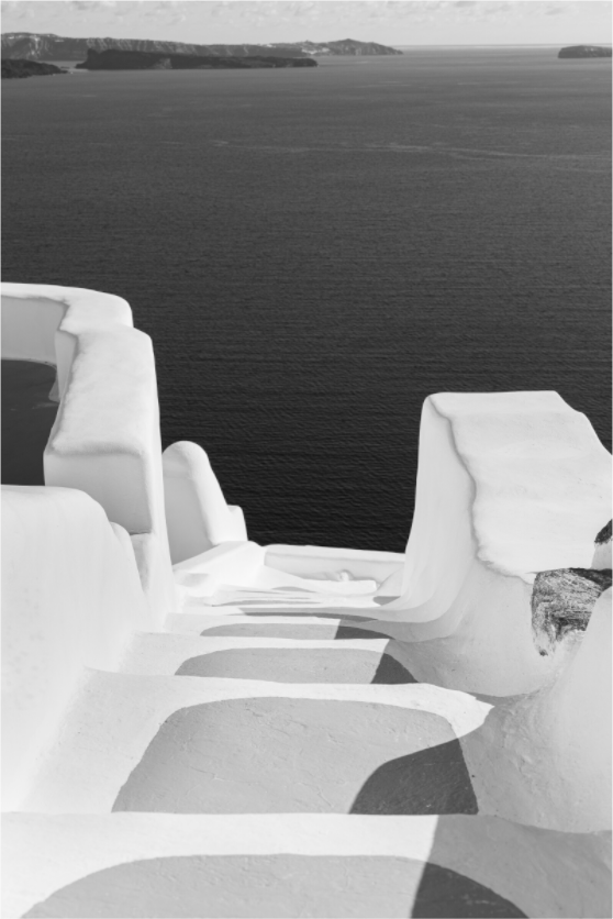 Black and white photograph of whitewashed steps descending toward the Aegean Sea in Oia, Santorini