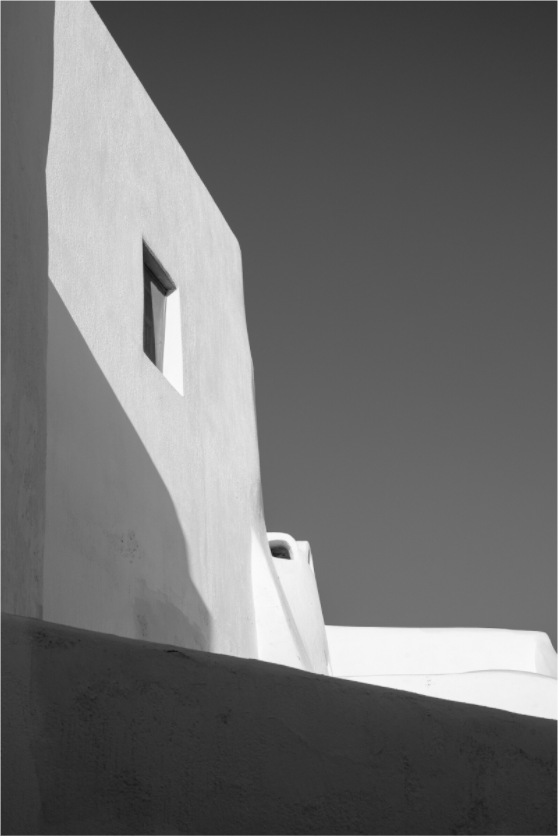 Black and white fine art photograph of a white Cycladic building with geometric shadows in Emborio, Santorini.