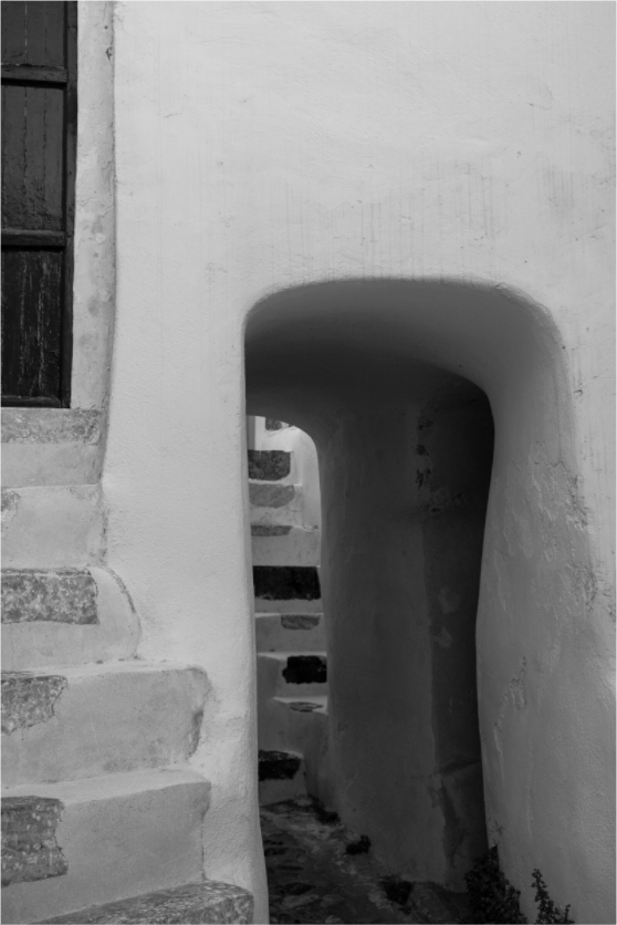 Black and white photograph of a narrow Cycladic passage and stone steps in Emborio, Santorini