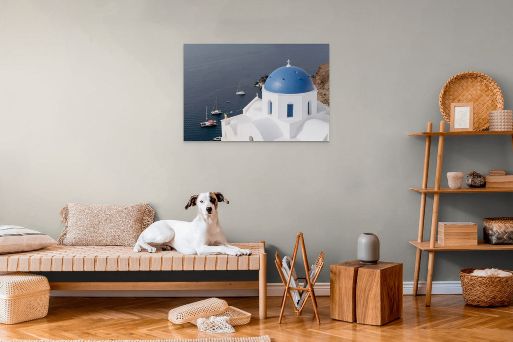 Iconic blue dome overlooking the Santorini caldera with sailboats drifting across the Aegean Sea.