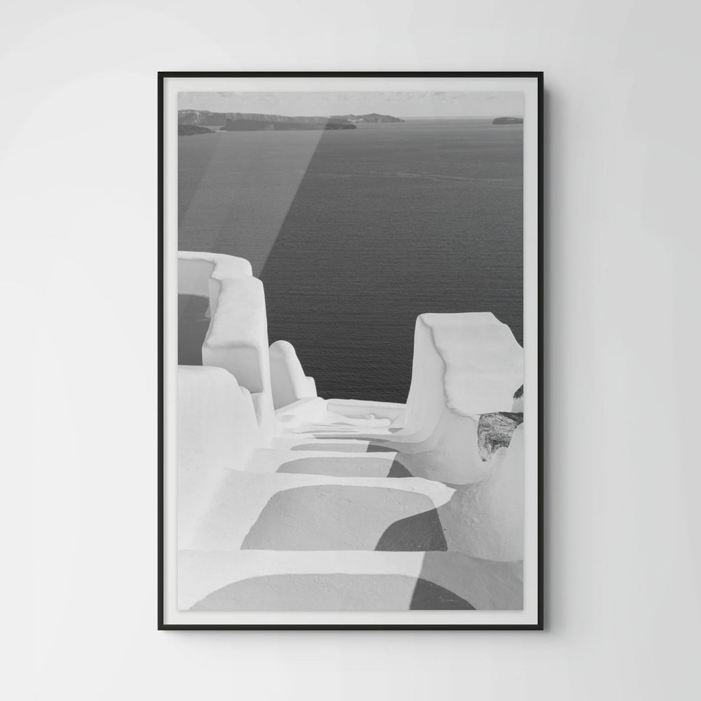 Black and white photograph of whitewashed steps descending toward the Aegean Sea in Oia, Santorini