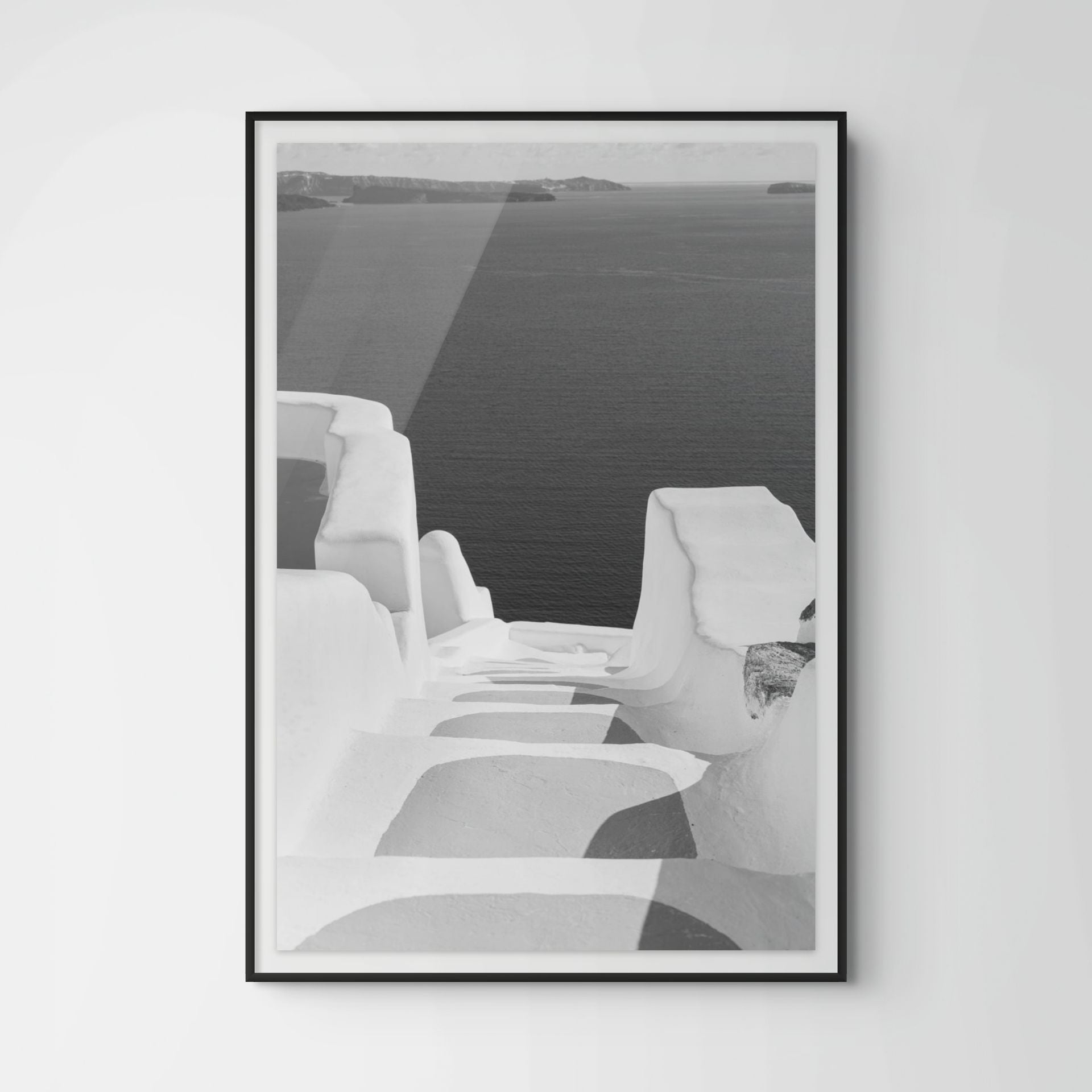 Black and white photograph of whitewashed steps descending toward the Aegean Sea in Oia, Santorini