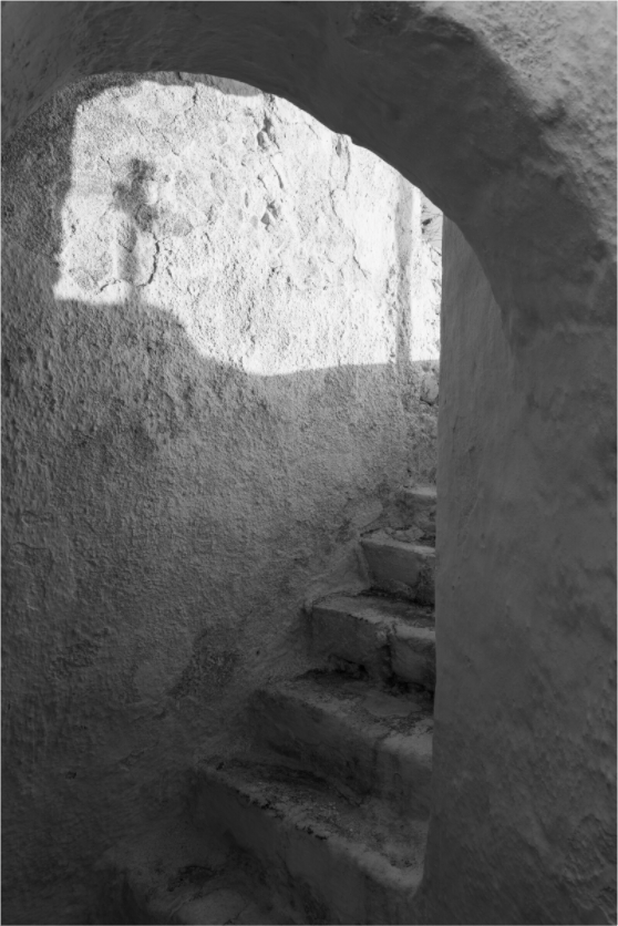 Black and white fine art photograph of a stone passage and staircase in Santorini, Greece – The Passage by Eva Rendl Studio